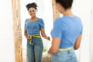 Happy Black Girl After Weight Loss Measuring Waist At Home