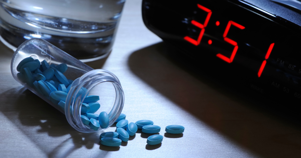 Spilled sleeping pills beside a clock showing 3:51 AM — symbolizing insomnia and dependence on medication.
