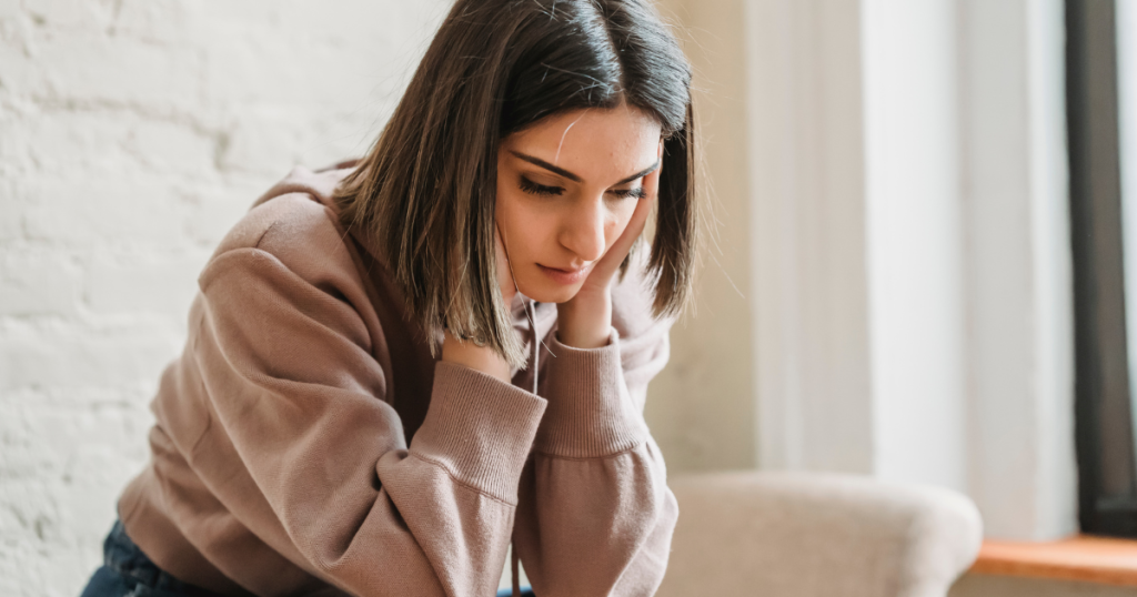 Young women feeling overwhelmed and worrying. She is emotionally drained, symbolizing chronic stress and burnout.
