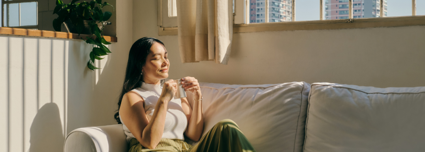 Woman peacefully enjoying tea on the couch after a relaxation hypnosis session in Edmonton.